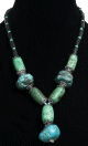 Collier ethnique artisanal imitation pierres vertes cylindrees et de grosses pierres bleues difformes agencees de perles et de tubes