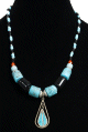 Collier ethnique artisanal imitation pierres cylindrees noires et bleues agrementees de perles multicolores et d'un pendentif