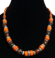 Collier ethnique artisanal imitation corail orange assorti de breloques marrons et de perles rouges ainsi que quelques pieces en metal